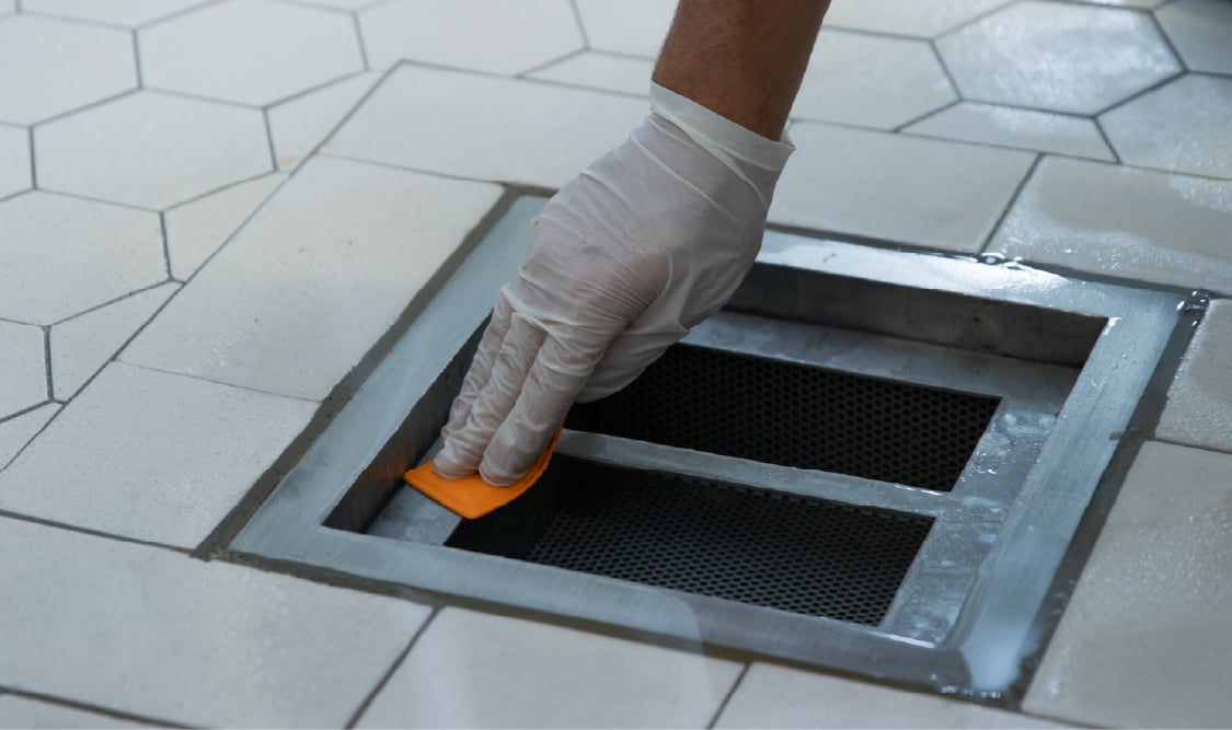 Food safety technician swabbing drain