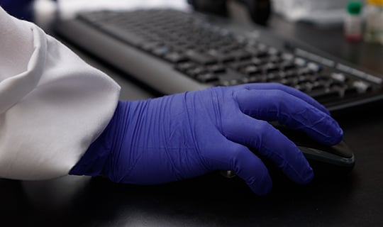 Lab technician in a white coat performing allergen testing in a controlled environment, using specialized equipment on a clean workbench, representing Neogen’s allergen analysis services.