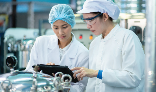 Two female food production workers reviewing environmental monitoring data.