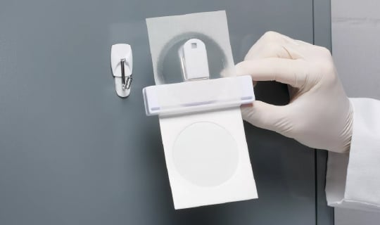 A hand holding a Neogen Petrifilm RYM Plate with plate clip for air sampling method