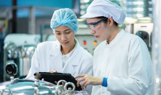 Two female food production workers reviewing environmental monitoring data.