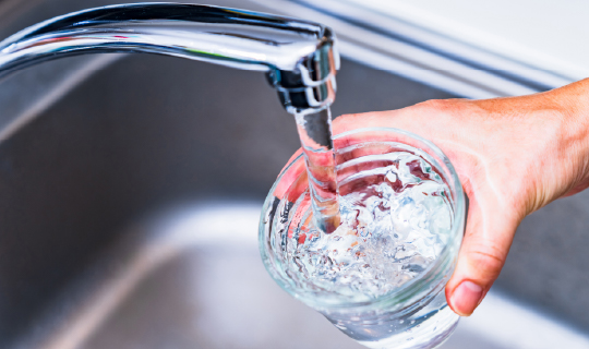 drinking glass being filled with water in a sink