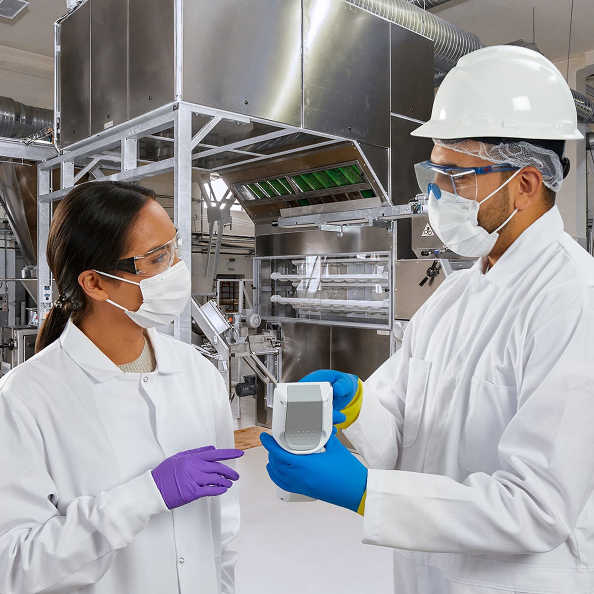 Profesionales de la industria alimentaria realizando monitoreo ambiental microbiológico en planta, con equipo de protección personal, como cubrebocas y guantes, en zonas críticas de procesamiento de alimentos.
